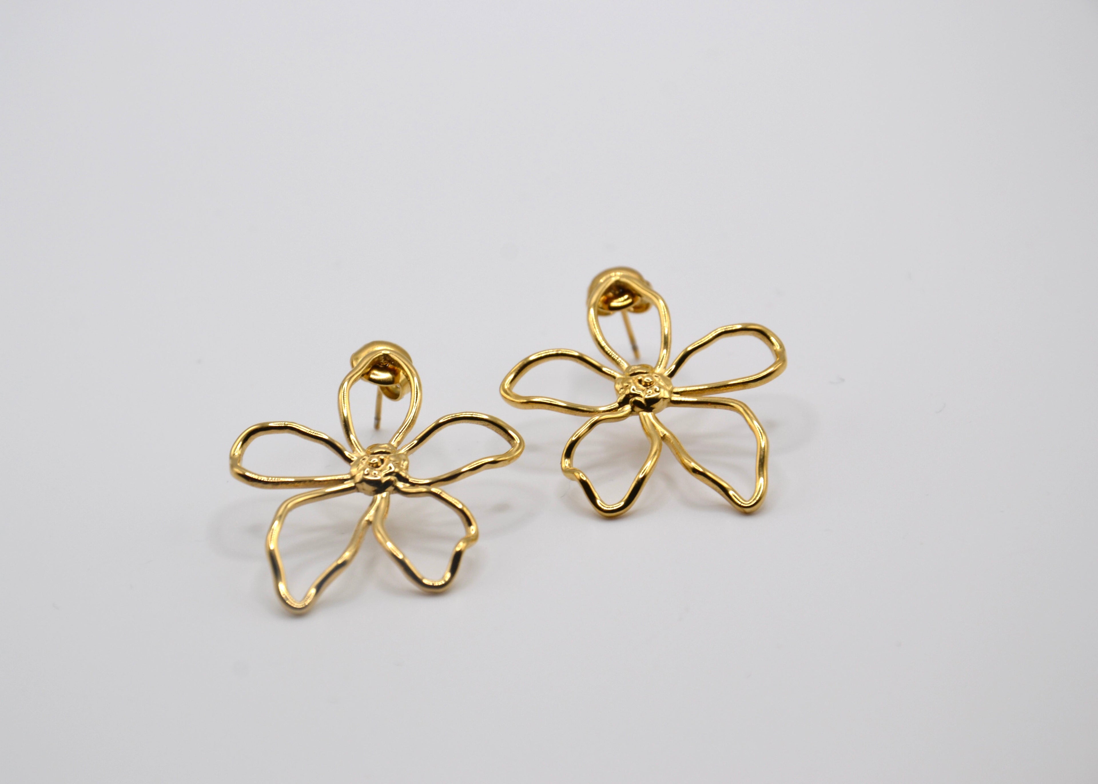Boucles d’oreilles dorées en forme de fleur sur fond blanc, bijoux fantaisie élégants