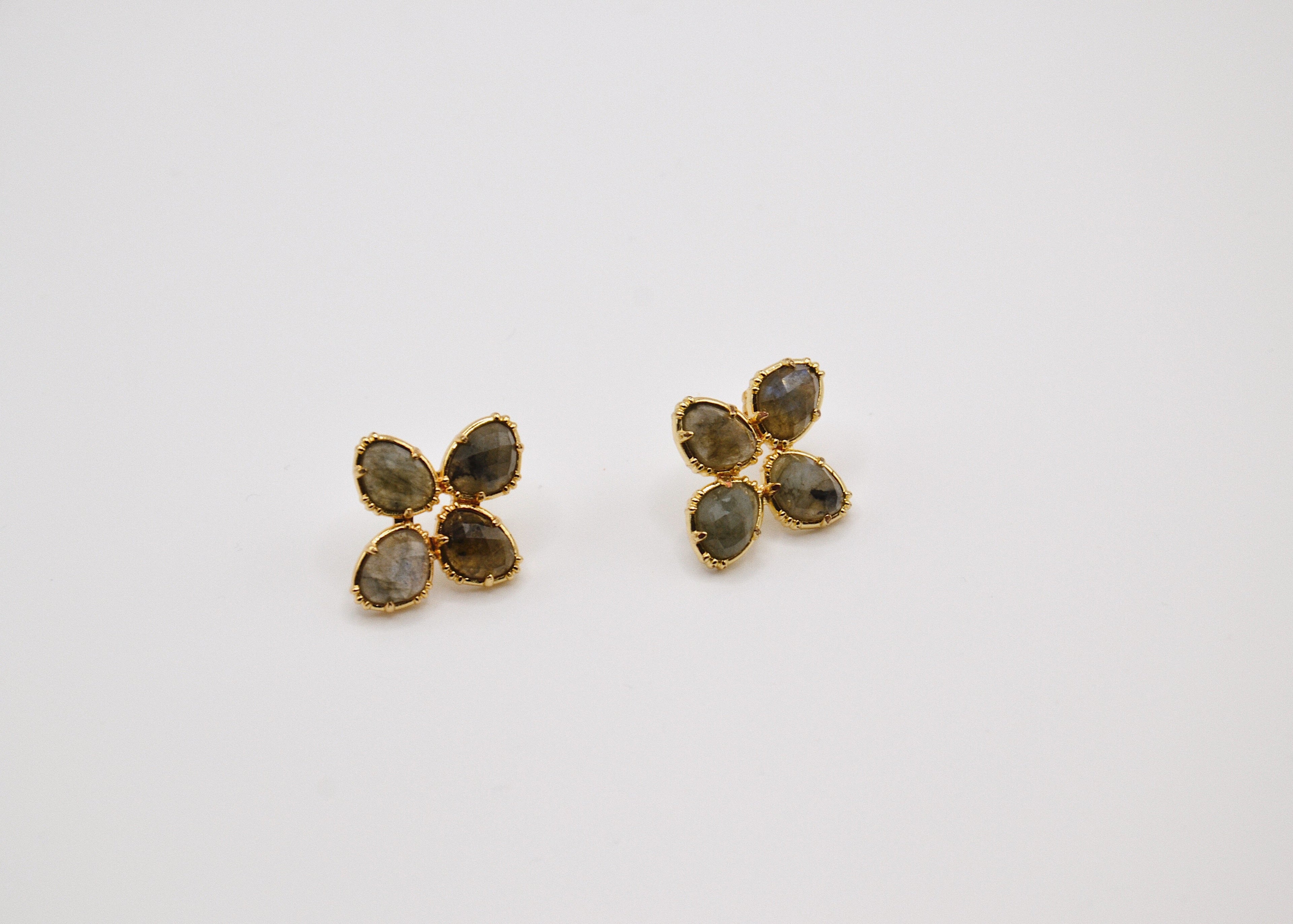 Boucles d’oreilles dorées fleurs quatre pétales pierres naturelles sur fond blanc