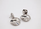 Boucles d’oreilles créoles argentées modernes effet ondulé sur fond blanc minimaliste