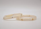 Bracelets tube ivoire avec détails dorés et argentés sur fond blanc, bijoux minimalistes