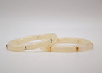 Bracelets jonc en jade crème avec accents métalliques, fond blanc minimaliste