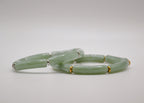 Bracelet en jade vert cylindrique avec séparateurs dorés sur fond blanc, bijou élégant.