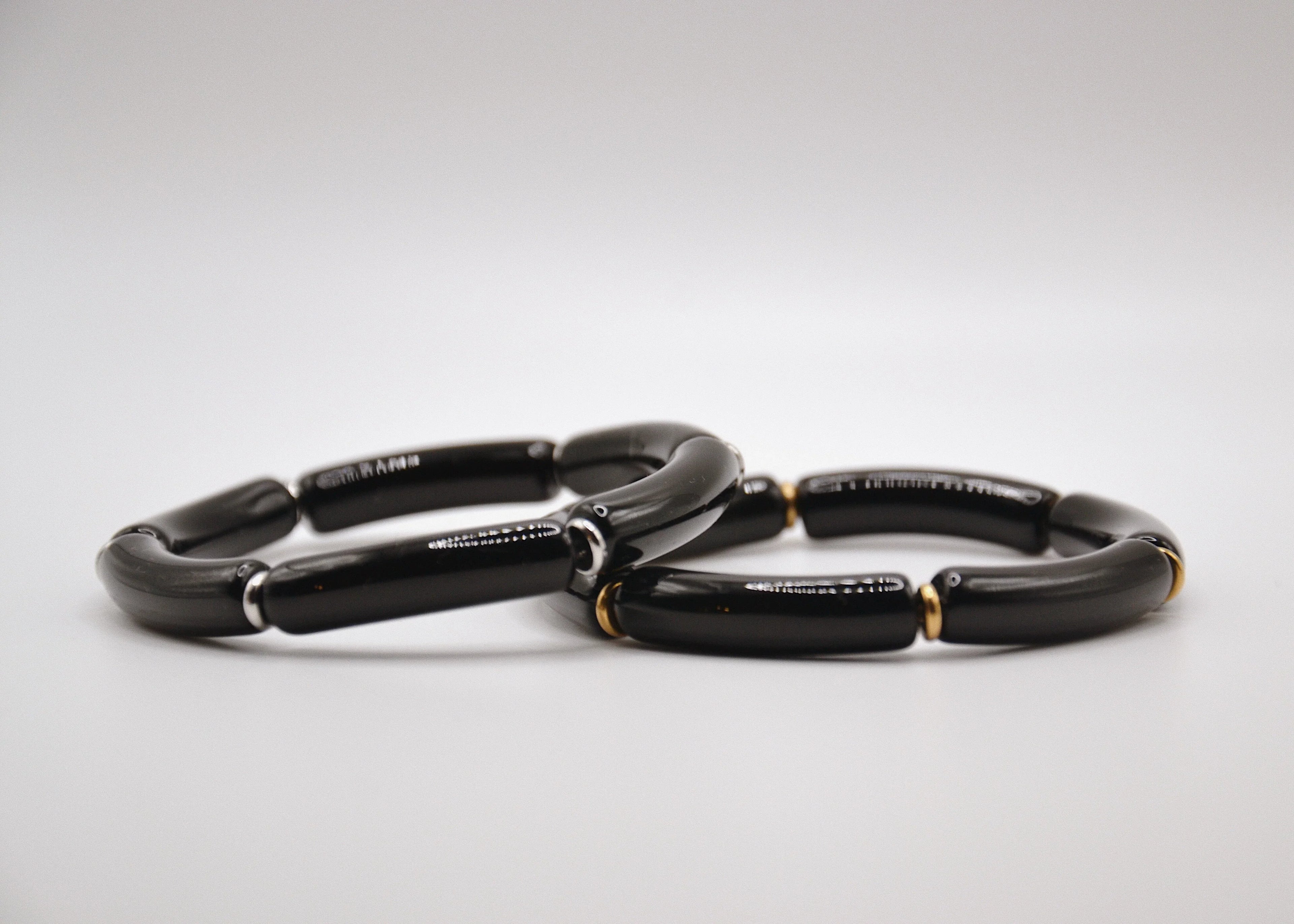 Bracelets en céramique noire avec accents dorés et argentés sur fond blanc, bijoux élégants