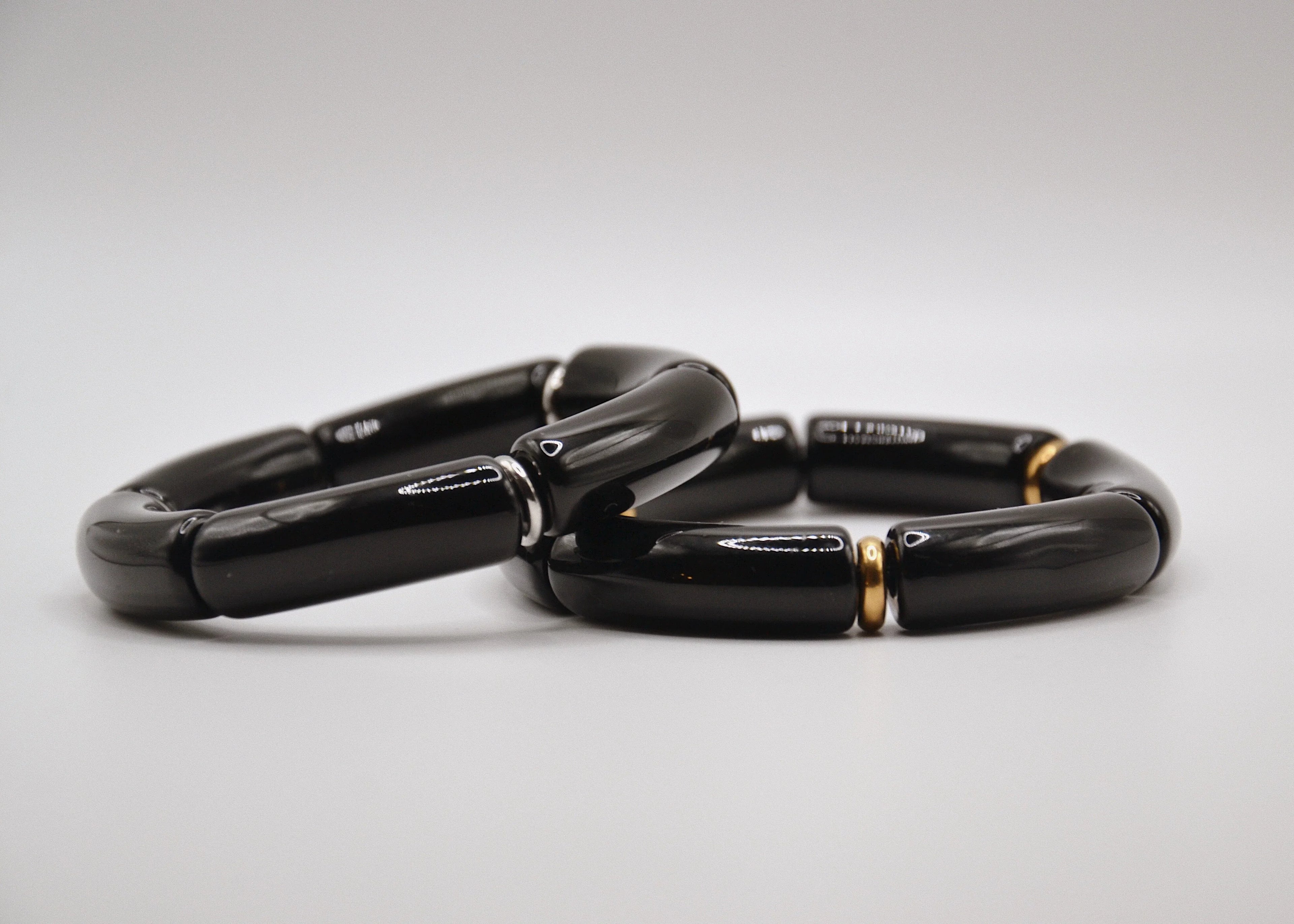 Bracelet moderne en céramique noire segmentée avec détails dorés sur fond blanc