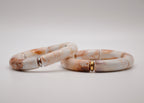 Bracelets en céramique marbrée blanc et beige avec accents dorés sur fond blanc