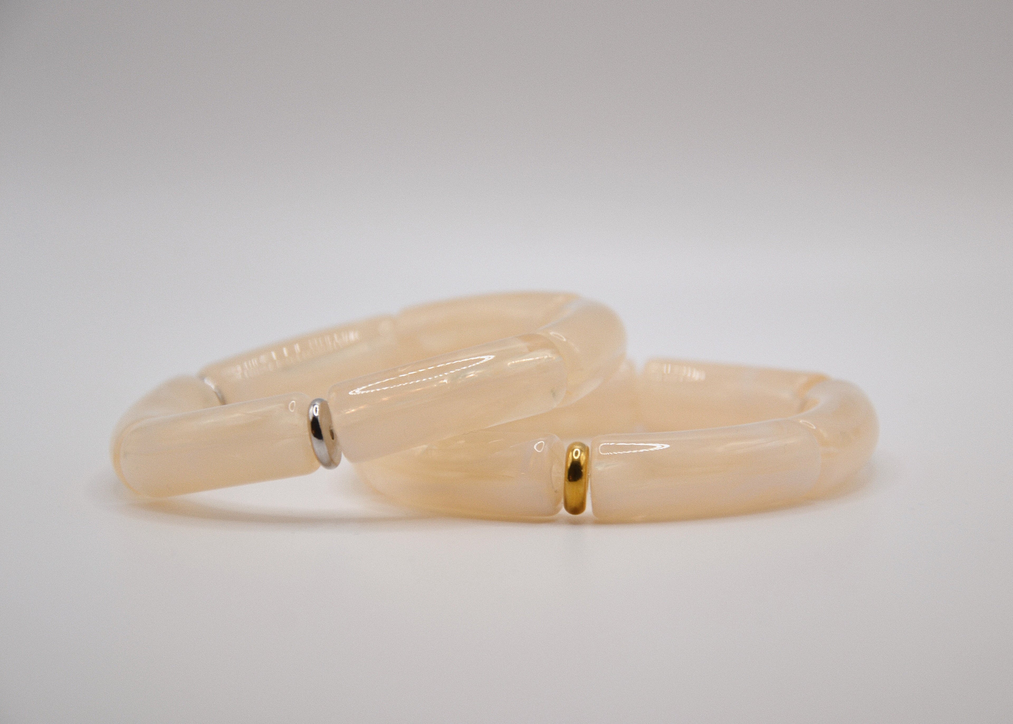 Bracelets en résine beige avec accents dorés et argentés sur fond blanc, bijoux femme tendance.