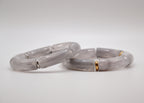 Bracelets en résine grise avec détails dorés, bijoux tendance sur fond blanc minimaliste