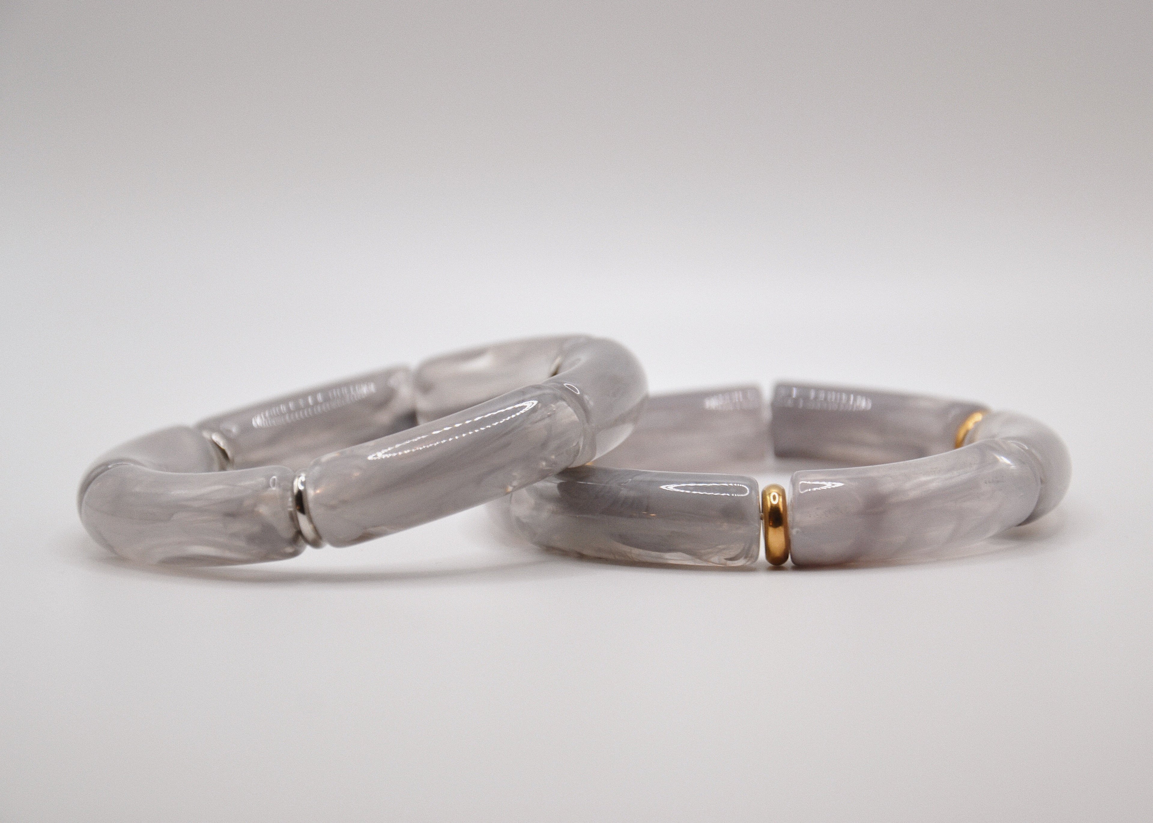 Bracelets en résine grise avec détails dorés, bijoux tendance sur fond blanc minimaliste