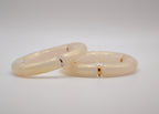 Deux bracelets en résine beige crème, détails dorés et argentés, sur fond blanc.