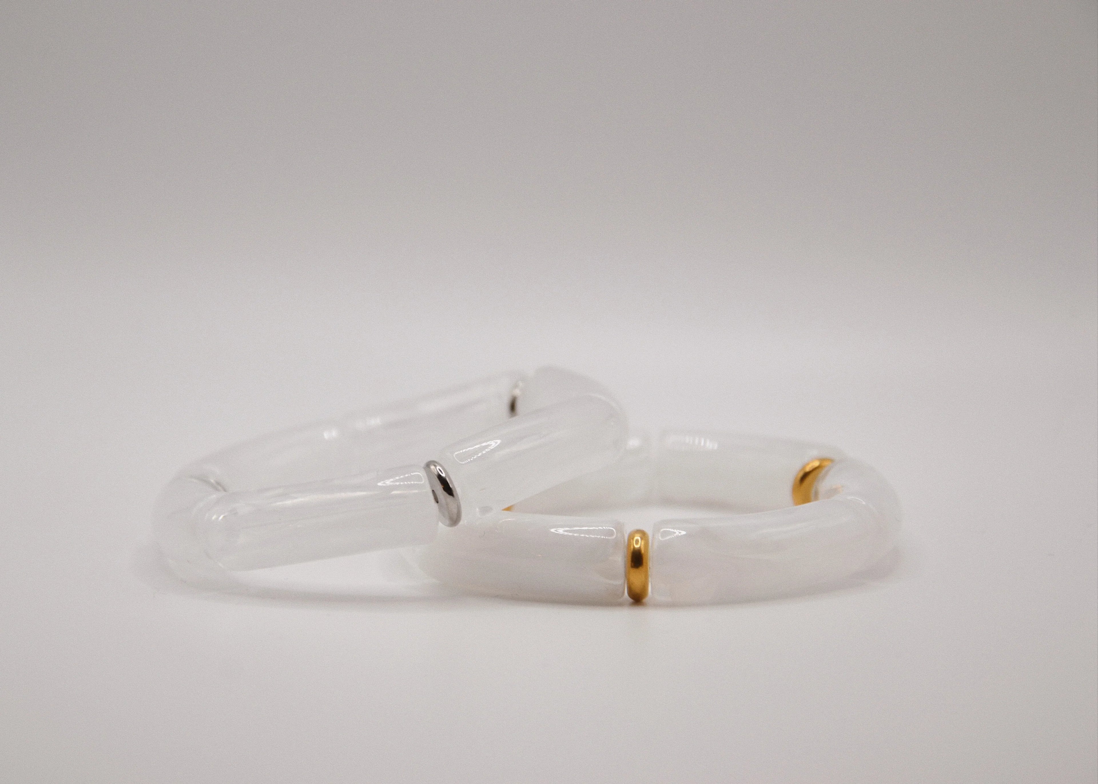 Bracelets en résine blanche, accents dorés et argentés, fond blanc minimaliste