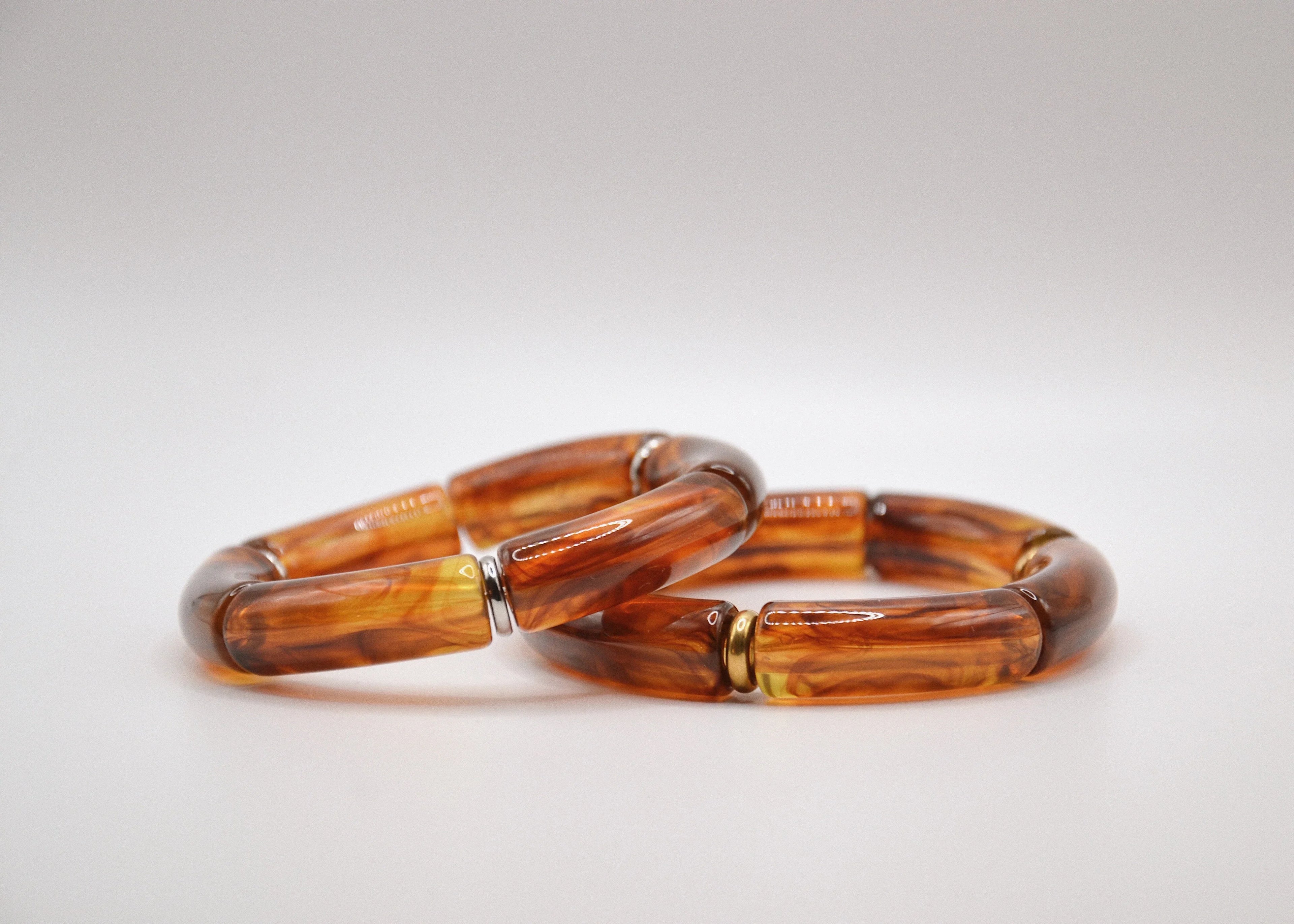 Deux bracelets en résine marron effet marbré sur fond blanc, bijoux tendance.