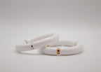 Deux bracelets céramique blanche avec accents dorés et argentés sur fond blanc minimaliste
