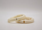 Bracelets en résine ivoire sur fond blanc, détails dorés et argentés, bijoux modernes élégants