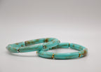 Deux bracelets turquoise en céramique avec accents dorés sur fond blanc, bijou tendance