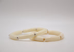 Deux bracelets ivoire articulés avec détails dorés et argentés sur fond blanc minimaliste