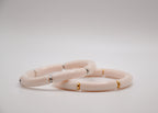 Bracelets roses en céramique avec accents dorés et argentés sur fond blanc.