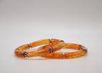 Bracelets en résine orange translucide pour femme, posés sur fond blanc, bijoux tendance