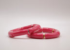 Bracelets rose vif en résine avec accents dorés, bijoux mode sur fond blanc minimaliste