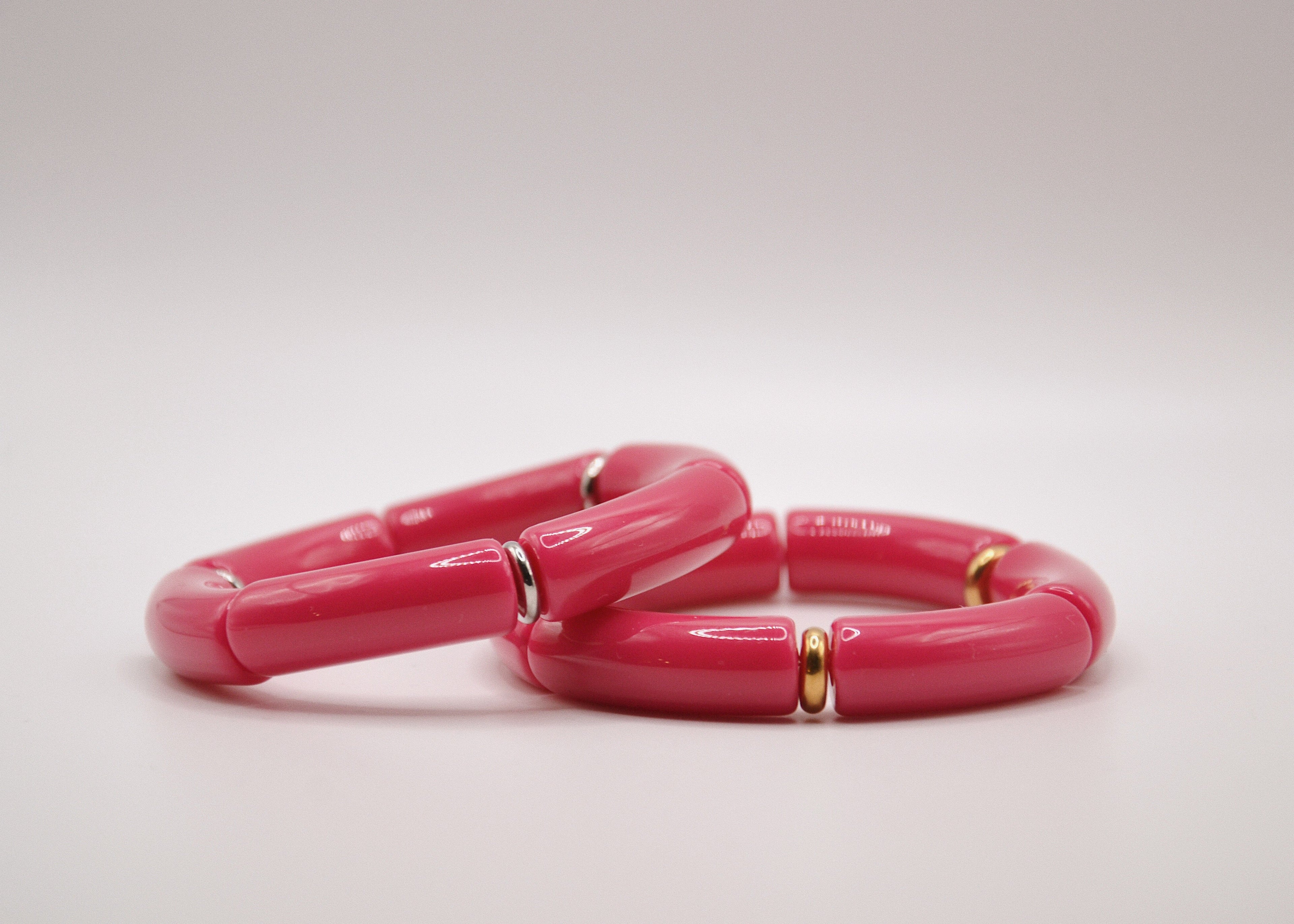 Bracelets rose vif en résine avec accents dorés, bijoux mode sur fond blanc minimaliste