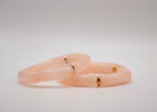Deux bracelets transparents rose clair avec anneaux dorés et argentés sur fond blanc