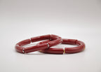 Bracelets rouges en résine avec détails dorés et argentés sur fond blanc, bijou moderne