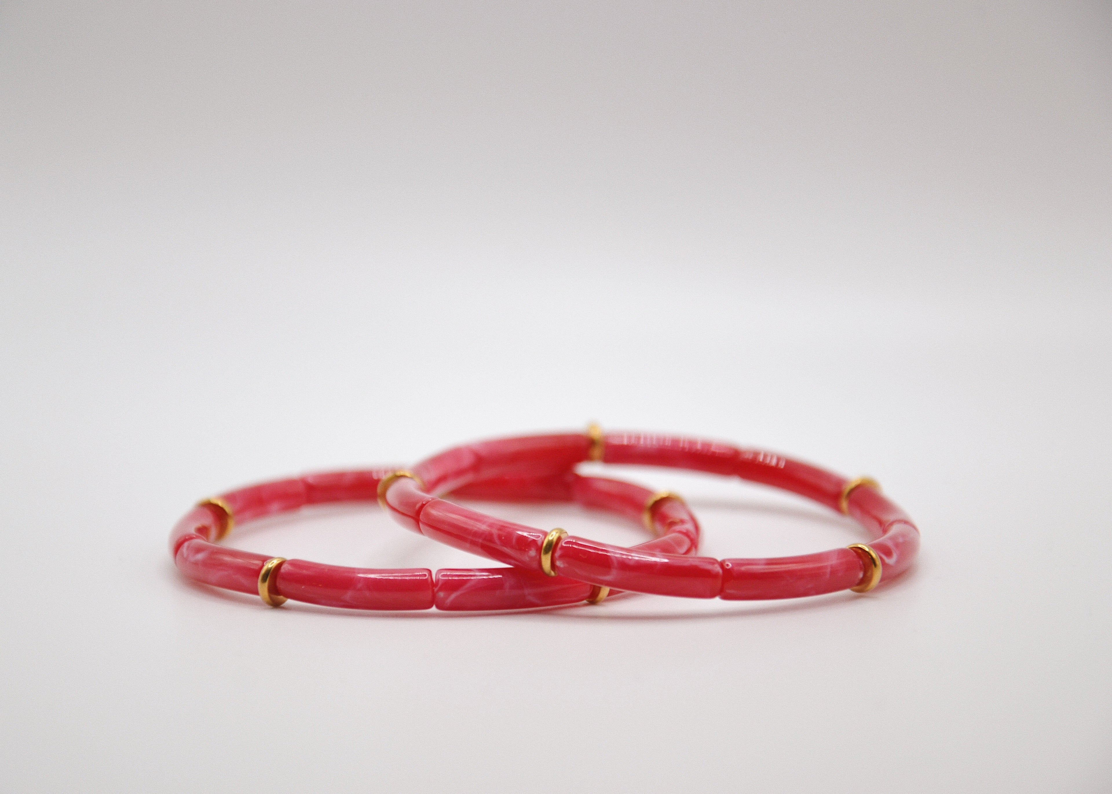 Bracelets rose en résine avec accents dorés sur fond blanc, bijou tendance minimaliste