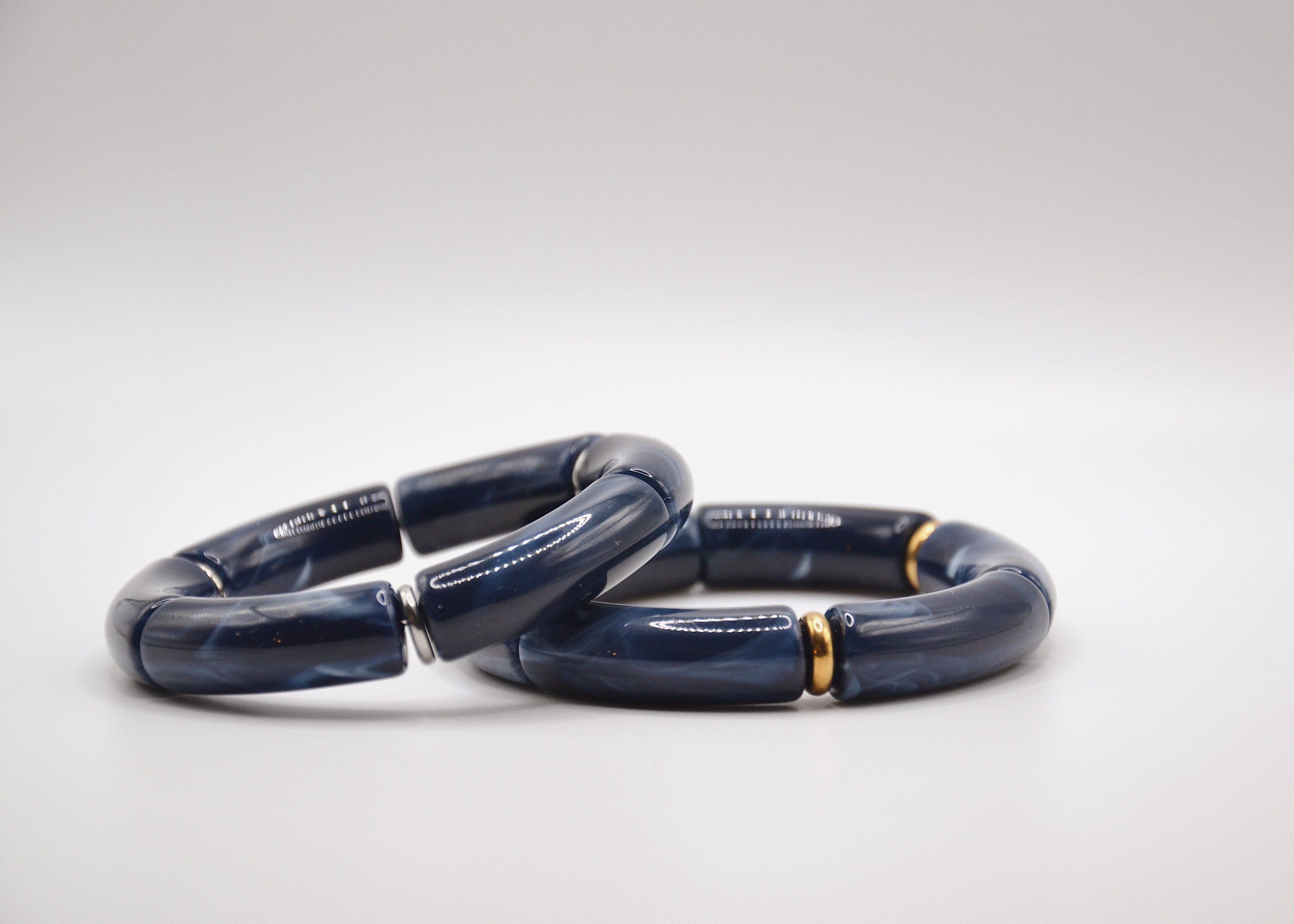 Bracelets en résine bleu foncé avec accents dorés, sur fond blanc, bijou tendance.