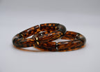 Bracelets effet écaille de tortue marron, segments dorés, sur fond blanc, accessoires bijoux.